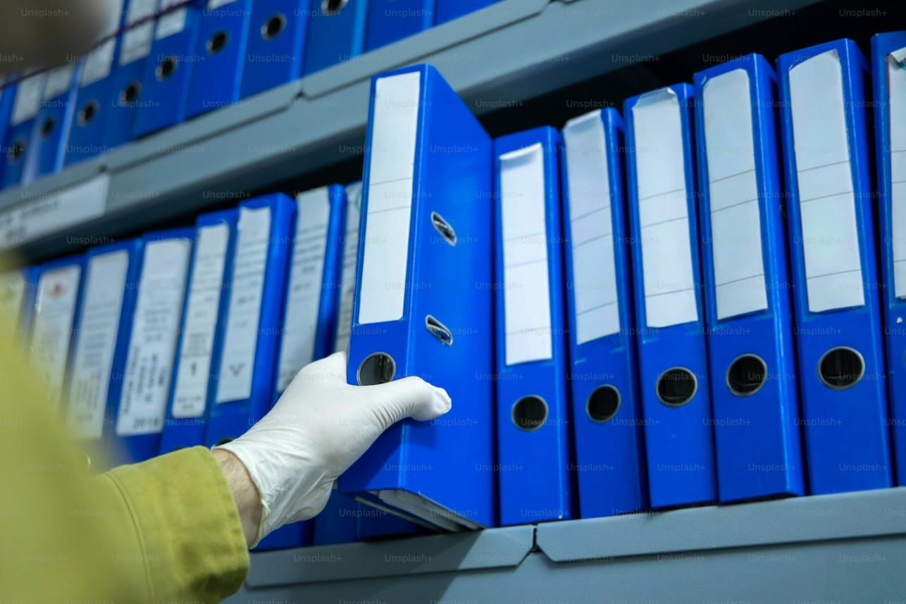 Hand pulling a blue binder from an industrial shelf